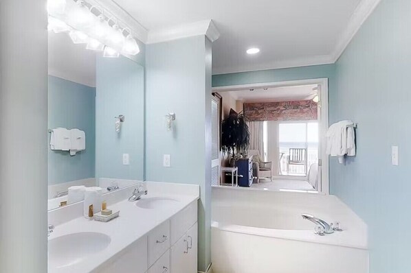 Een moderne badkamer met twee wastafels, een grote spiegel en een bad.