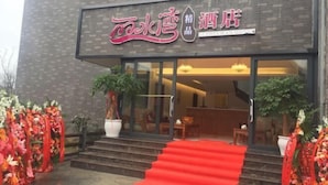 A hotel entrance with a red carpet, glass doors, and floral decorations. - Lishuiwan Hotel (Luoping)