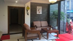 A modern living room with a sofa, armchair, and coffee table. There is a large window with a view of the outside. - Lishuiwan Hotel (Luoping)