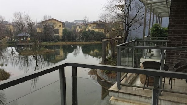 A view from a balcony overlooking a body of water with houses in the background. - Lishuiwan Hotel (Luoping)