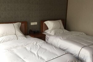 A hotel room with two beds, each with white bedding and wooden headboards.