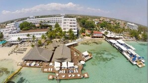 A resort with multiple buildings, a beach area with umbrellas, and a pier extending into the water. - Hotel Boca del Mar Playa Boca Chica Penthouse (Boca Chica)