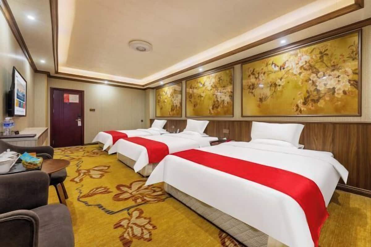 Habitación de hotel con dos camas, un escritorio, una silla y piso alfombrado.