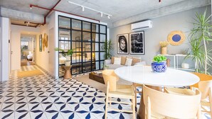 Un interior moderno con piso de diseño geométrico, una mesa redonda para comer y una zona de estar con sofá y sillones.
