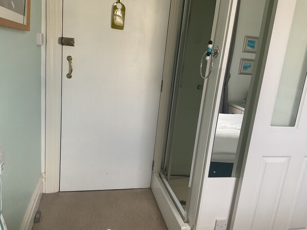 A room with a white door, a shower area, and a small window. - Merritt guest house (Paignton)