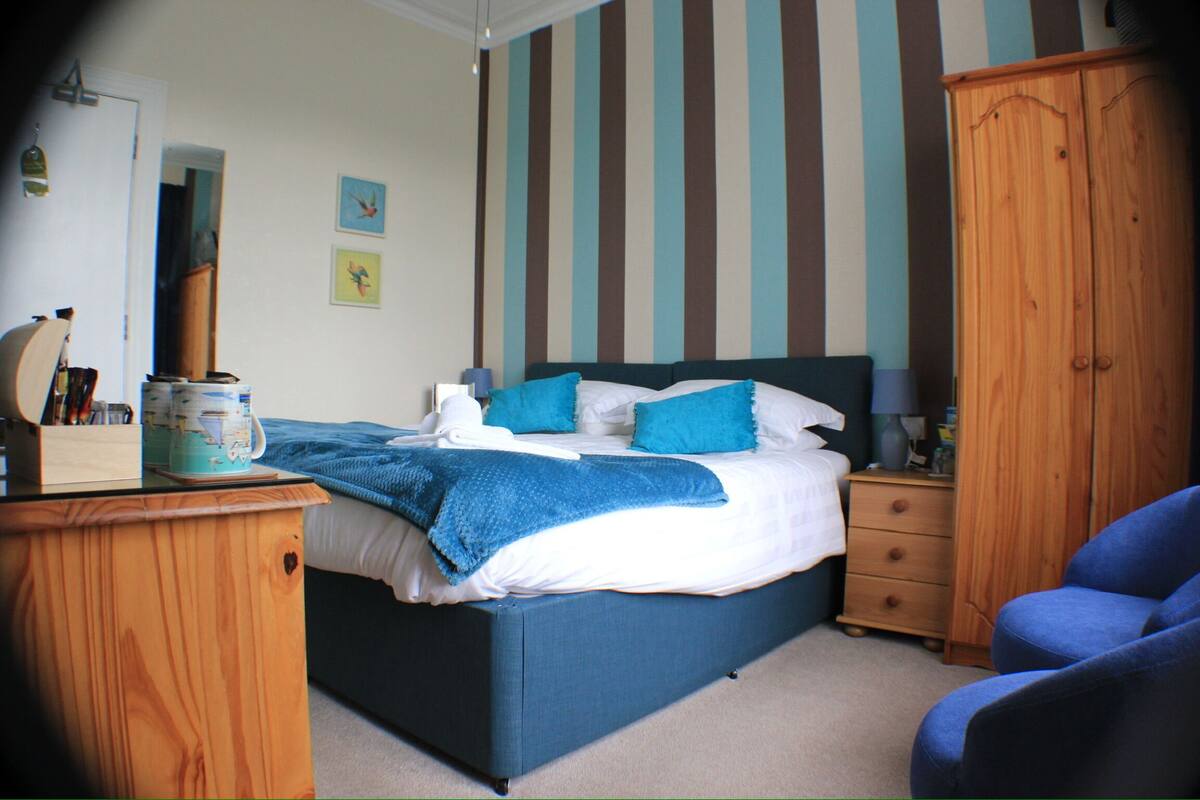 A bedroom with a bed, wooden wardrobe, and a chair.