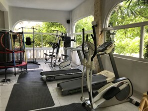 A home gym with exercise equipment including treadmills, an elliptical, and a trampoline. - Villa George (Kassandra)