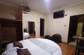 A bedroom with a bed, a desk, a chair, a TV, and a fan. - CONQUISTADOR HOTEL (Lima)