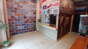 A reception area with a brick wall, a glass display case with logos, and a tiled floor with directional markers. - CONQUISTADOR HOTEL (Lima)