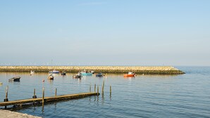 Ein ruhiger Hafen mit mehreren Booten, die an einer Steinmole vertäut sind.