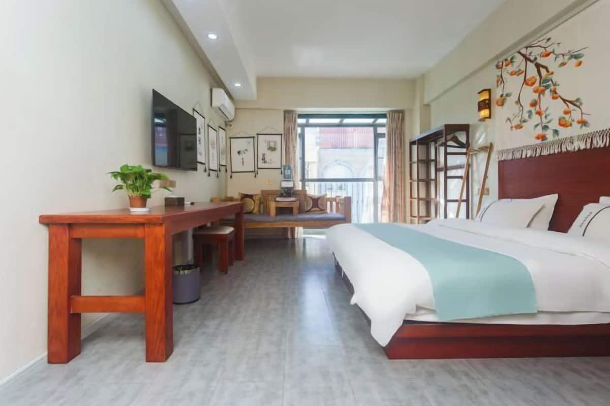 Ein Hotelzimmer mit einem Bett, einem Holztisch, einem Stuhl, einem kleinen Tisch und einer Topfpflanze.