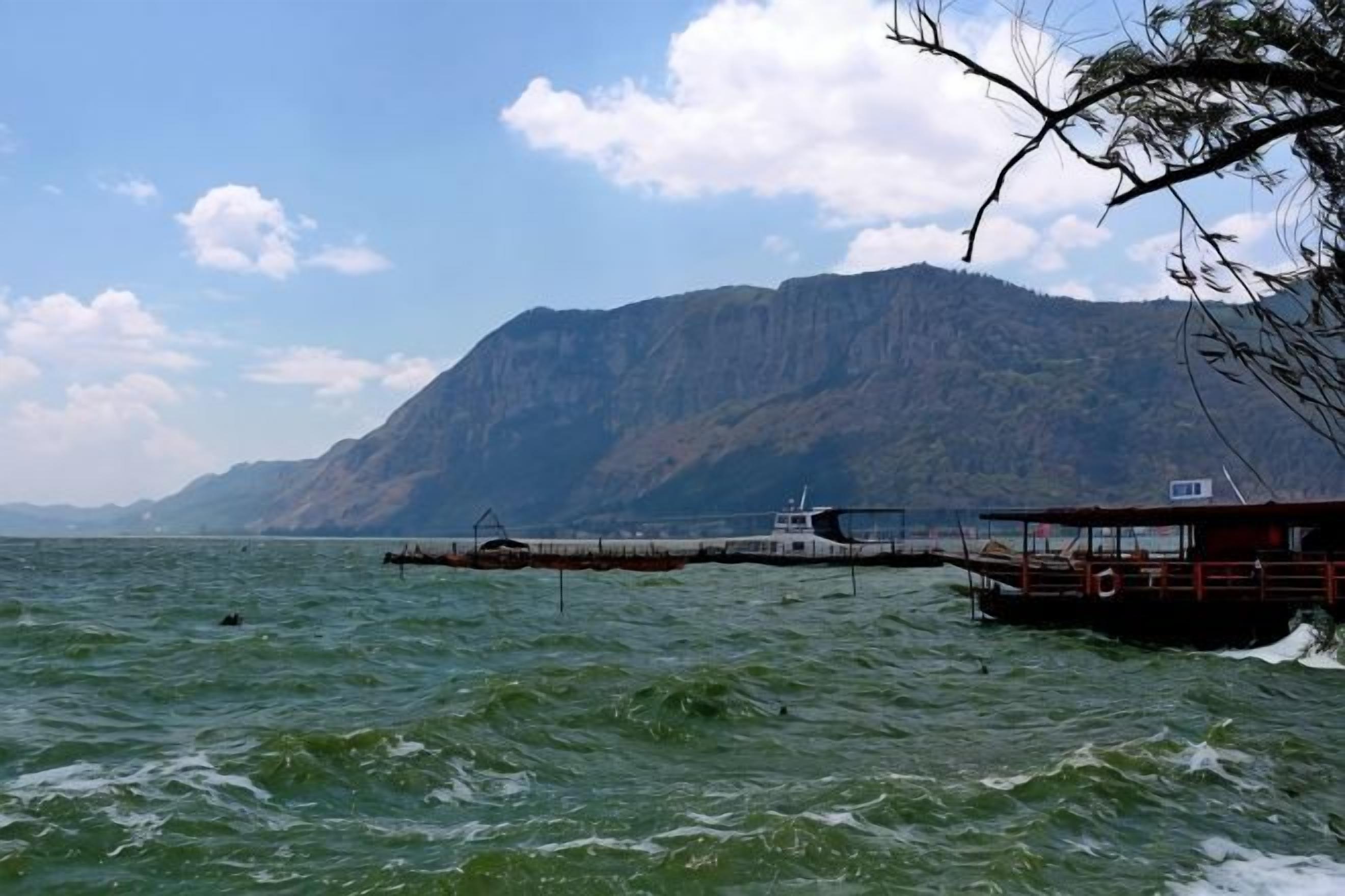 A boat docked at a pier with a mountainous backdrop.