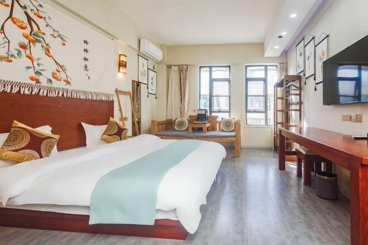Ein Hotelzimmer mit einem Bett, einem Schreibtisch, einem Stuhl, einem Fernseher und einem Fenster.