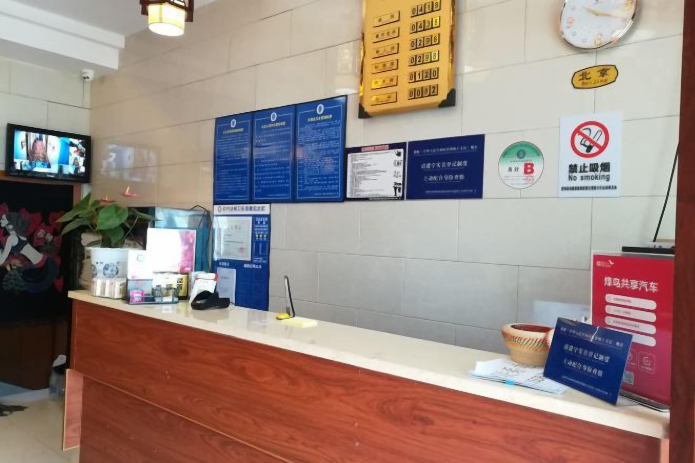 A reception desk with informational posters, a clock, and a no-smoking sign.