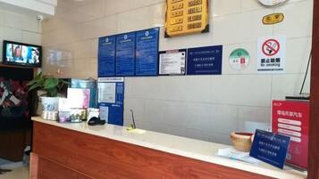 A reception desk with informational posters, a clock, and a no-smoking sign.
