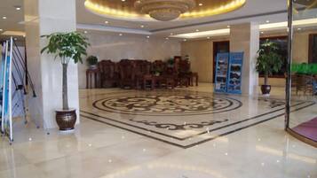 Un vestíbulo de hotel con una alfombra circular grande, muebles de madera y una araña.