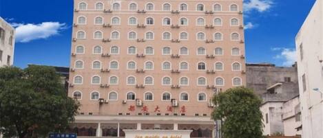 Un hotel de varios pisos con fachada uniforme, múltiples ventanas y un letrero que indica que se trata de un hotel.