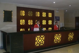 Una recepción con un fondo estampado, un cartel con información de las habitaciones y un aviso enmarcado en la pared.
