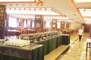 A banquet hall with multiple tables and chairs, a buffet setup, and a television screen. - Du an Hotel (Du'an)
