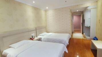 A hotel room with two beds, a nightstand, a mirror, and a wooden floor.