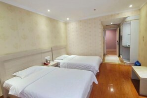 A hotel room with two beds, a nightstand, a mirror, and a wooden floor. - Du an Hotel (Du'an)