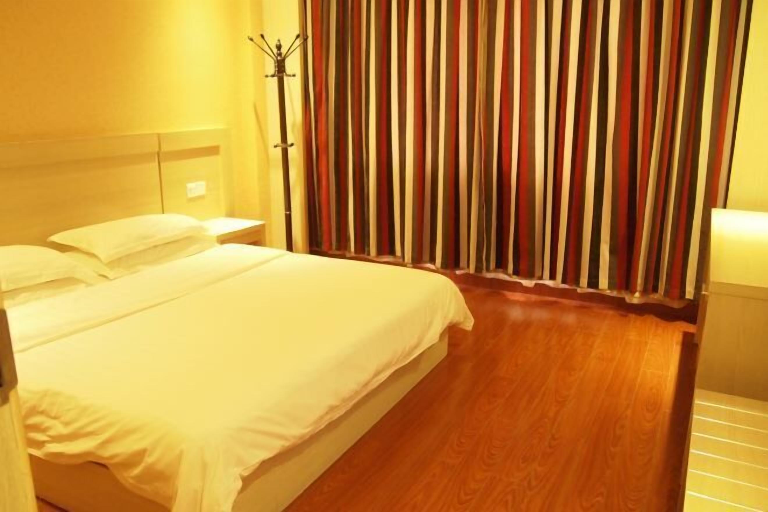 A hotel room with a bed, a nightstand, a lamp, and a curtain with vertical stripes.