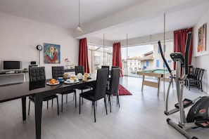 A modern living space with a dining area, a television, a painting, a treadmill, and a pool table. - Loft Cosy - Hypercentre - Sauna - 200m2 - Wifi (Graulhet)