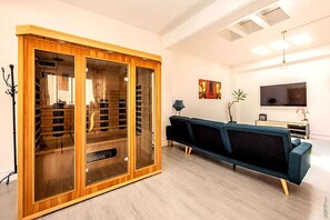 A modern living room with a wooden cabinet, a blue sofa, a television, and a painting on the wall. - Loft Cosy - Hypercentre - Sauna - 200m2 - Wifi (Graulhet)
