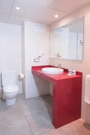A bathroom with a white toilet, a red sink vanity, and a large mirror. - Cye Salou Apartments (Salou)