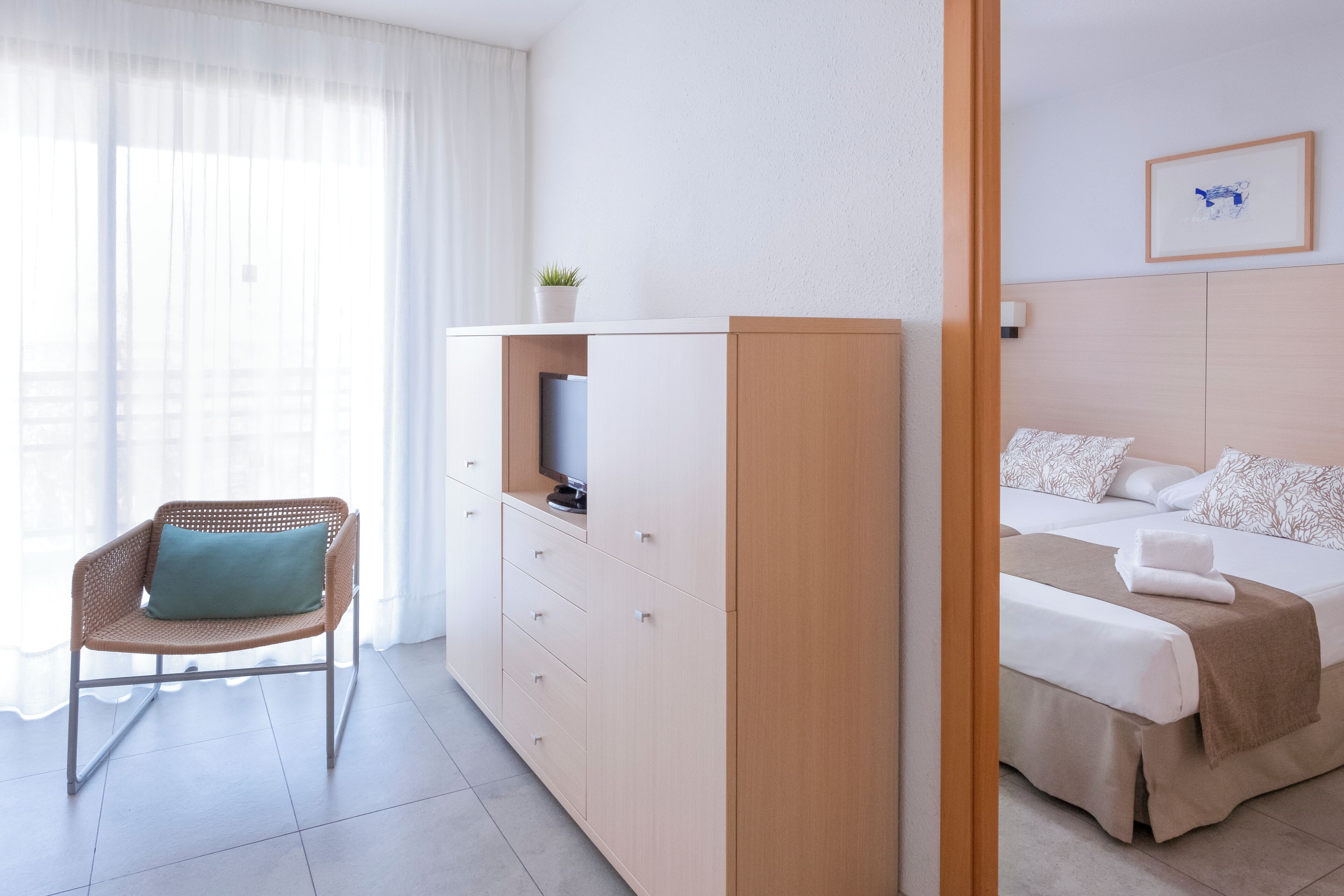 Une chambre d’hôtel avec un lit, une chaise, une télévision et un placard.