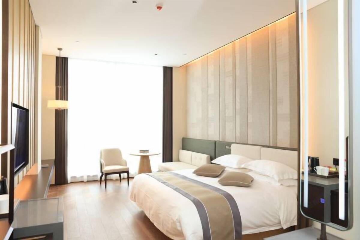 Une chambre d’hôtel moderne avec un grand lit, une télévision, une petite table et une chaise.