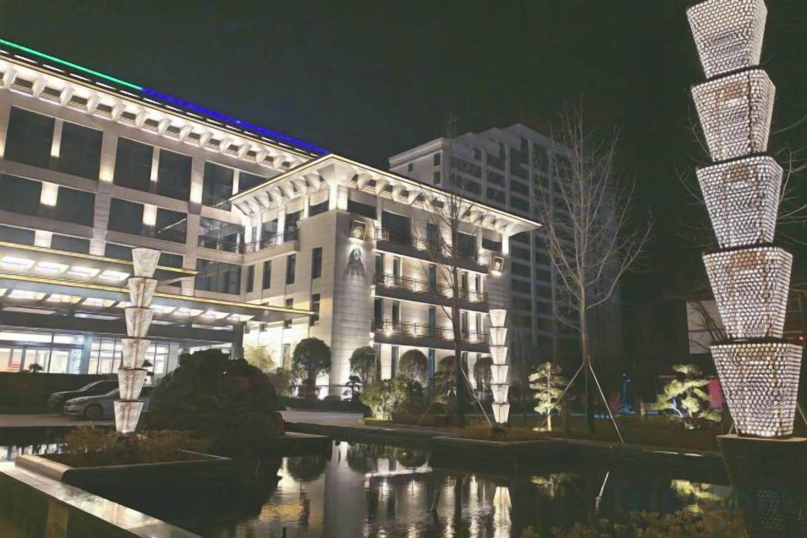 Un edificio moderno con una piscina reflectante y una estructura lumínica decorativa.
