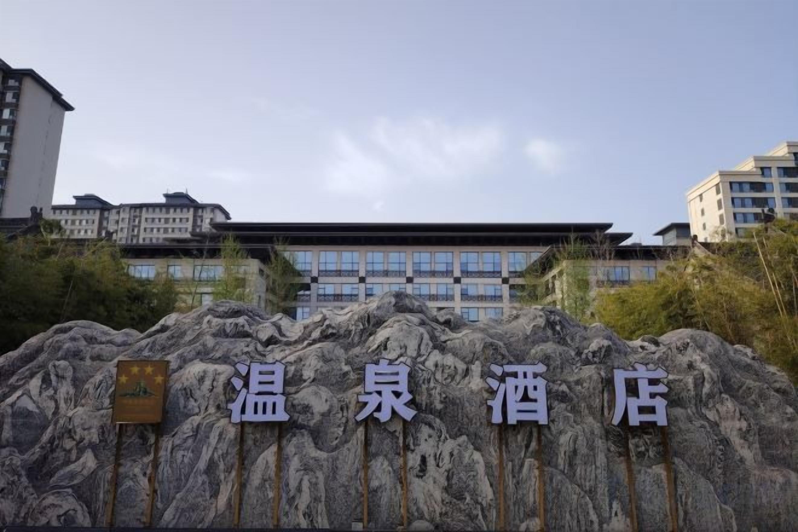 Entrada de hotel con fachada de piedra y un letrero con caracteres chinos.