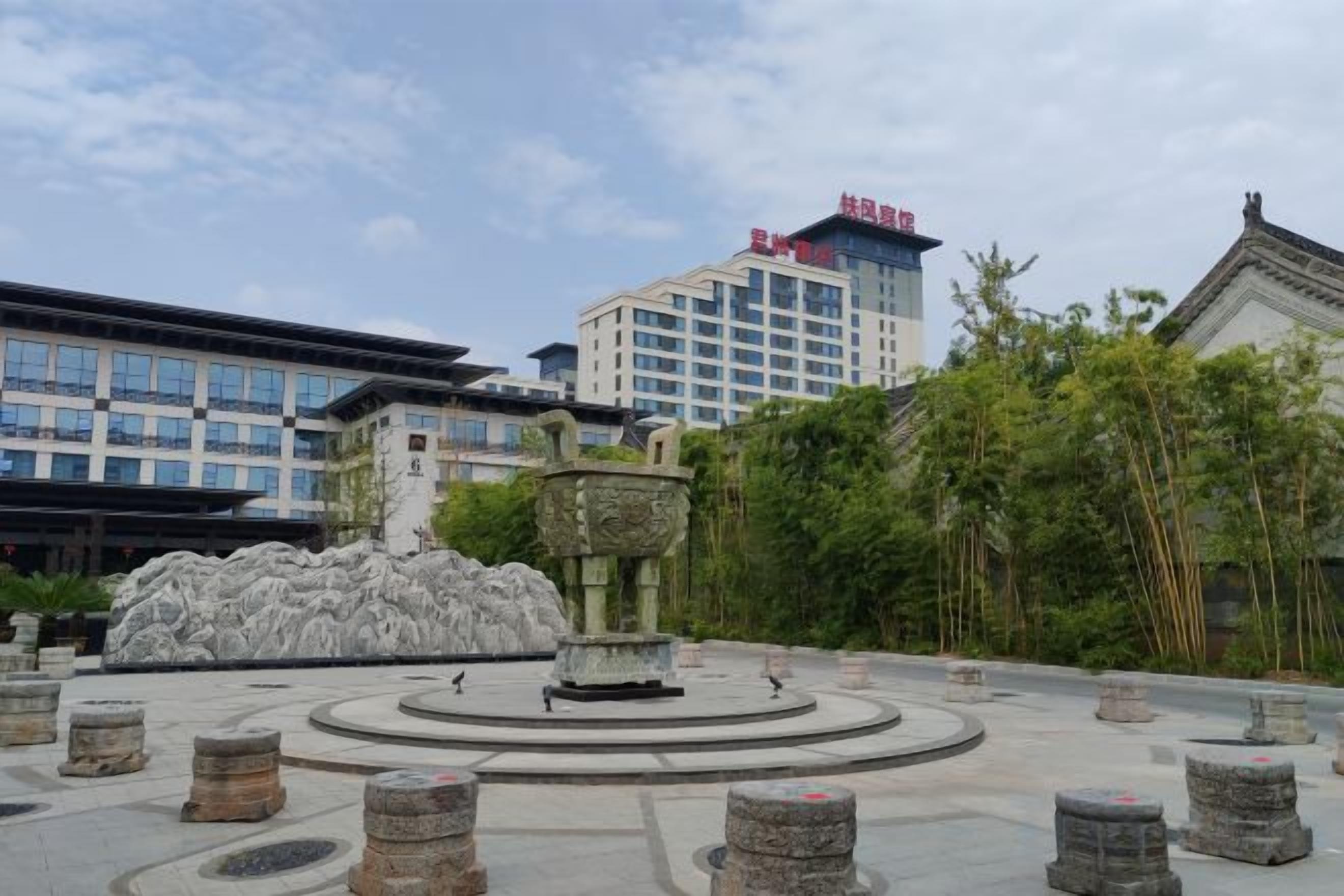 A courtyard with a central fountain, stone bollards, and traditional architecture.