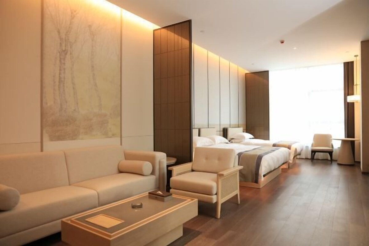 Een moderne hotelkamer met een groot bed, een bank, een fauteuil en een salontafel.