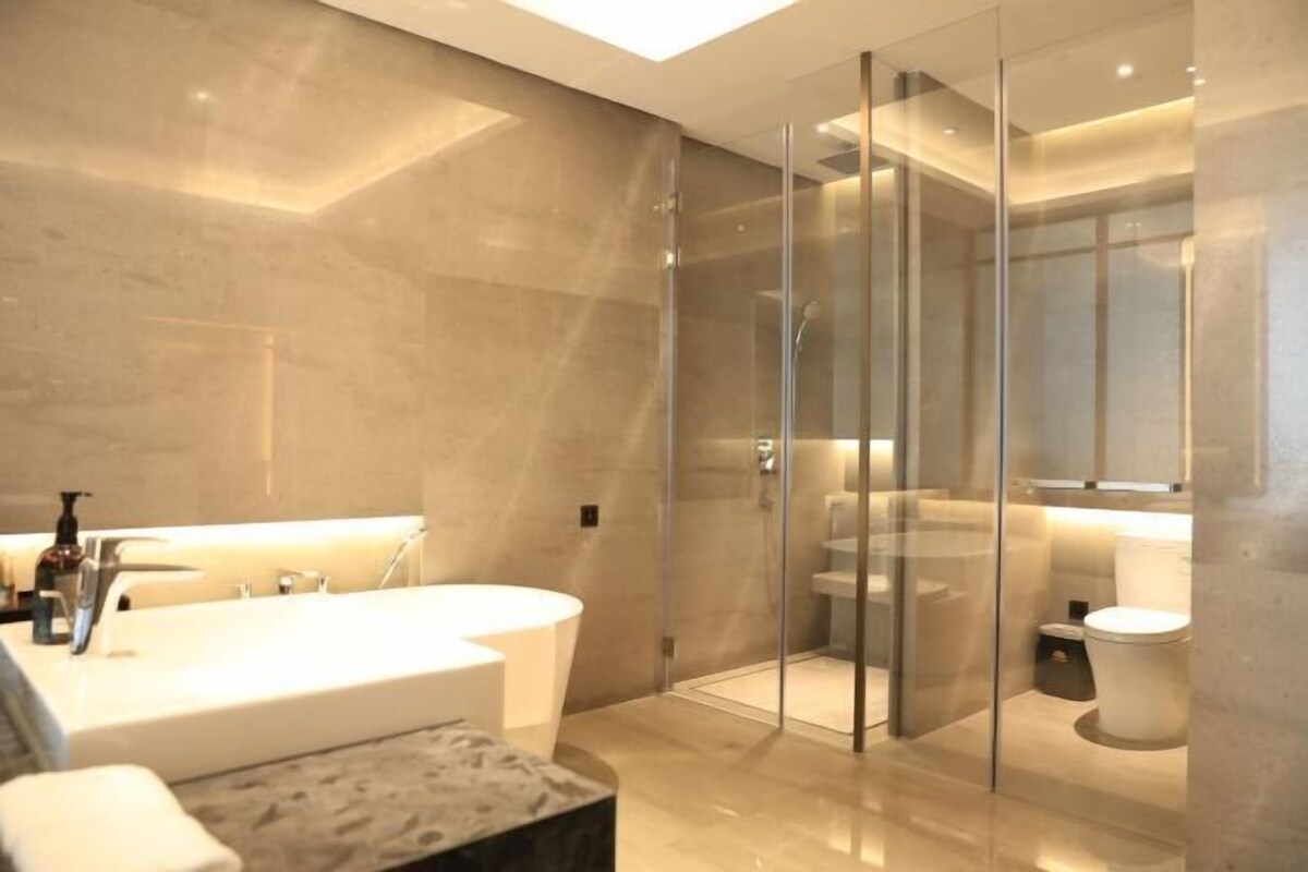 Een moderne badkamer met een douchecabine van glas, een vrijstaand bad en een toilet.
