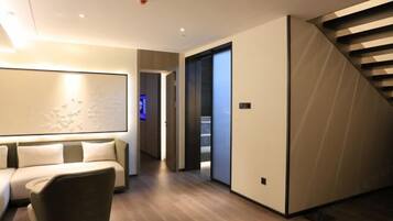 A modern interior with a sofa, a chair, a staircase, and a hallway leading to another room.