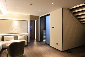 Een modern interieur met een bank, een stoel, een trap en een gang die naar een andere kamer leidt.