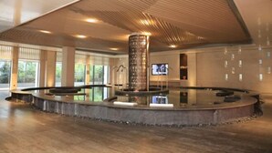 Een ruime binnenruimte met een centraal waterpartij, grote ramen en een modern plafondontwerp.