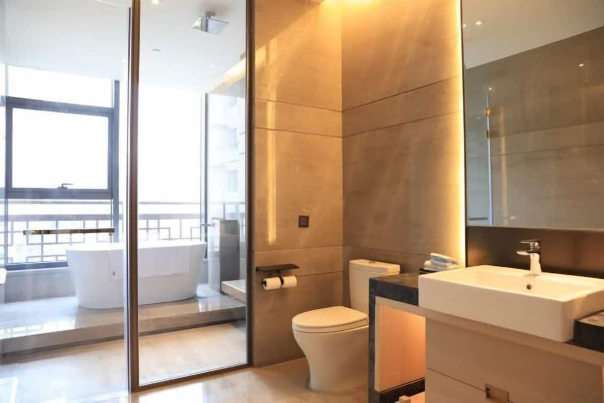 Une salle de bain moderne avec une paroi en verre, des toilettes, un lavabo et un grand miroir.
