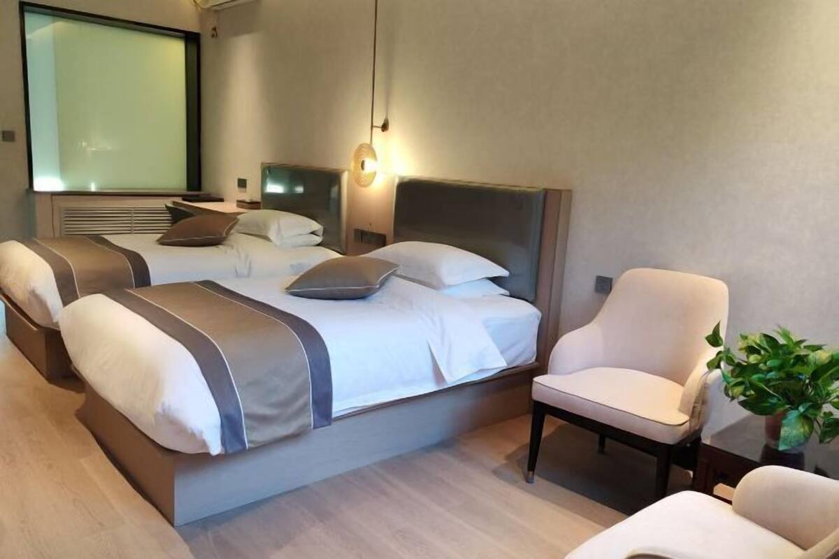 Une chambre d’hôtel moderne avec un grand lit, une table de chevet, une chaise et une plante en pot.
