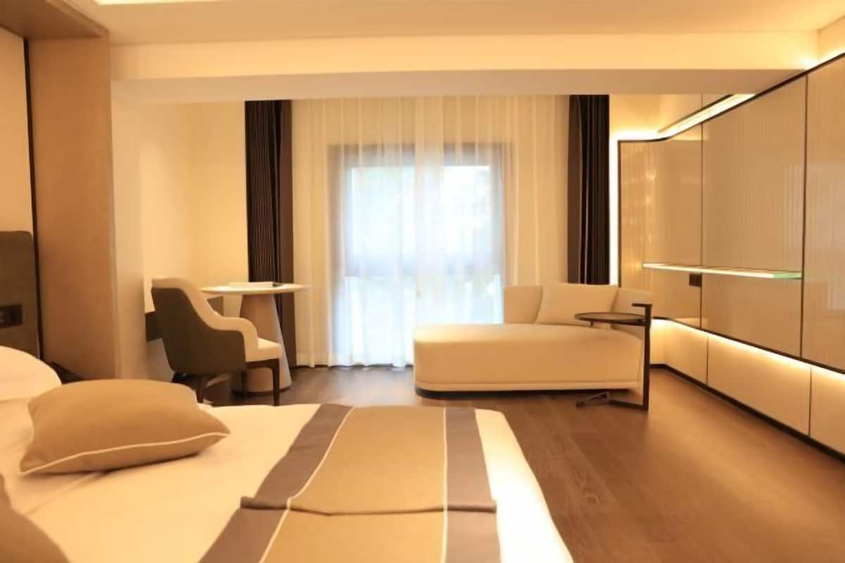 Une chambre d’hôtel moderne équipée d’un lit, d’un canapé, d’un bureau et d’une télévision.