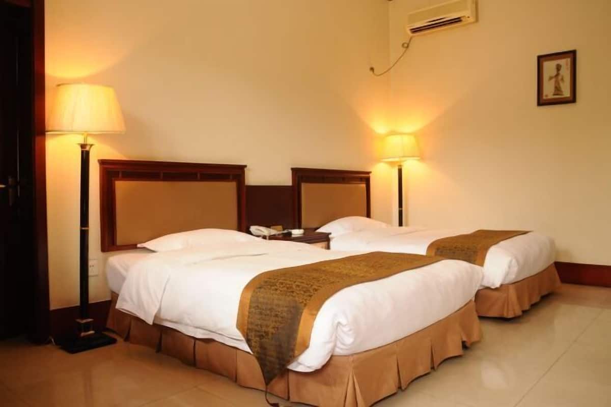 Une chambre d’hôtel avec deux lits, chacun doté d’une tête de lit, de lampes de chevet et d’un téléphone sur la table de chevet.