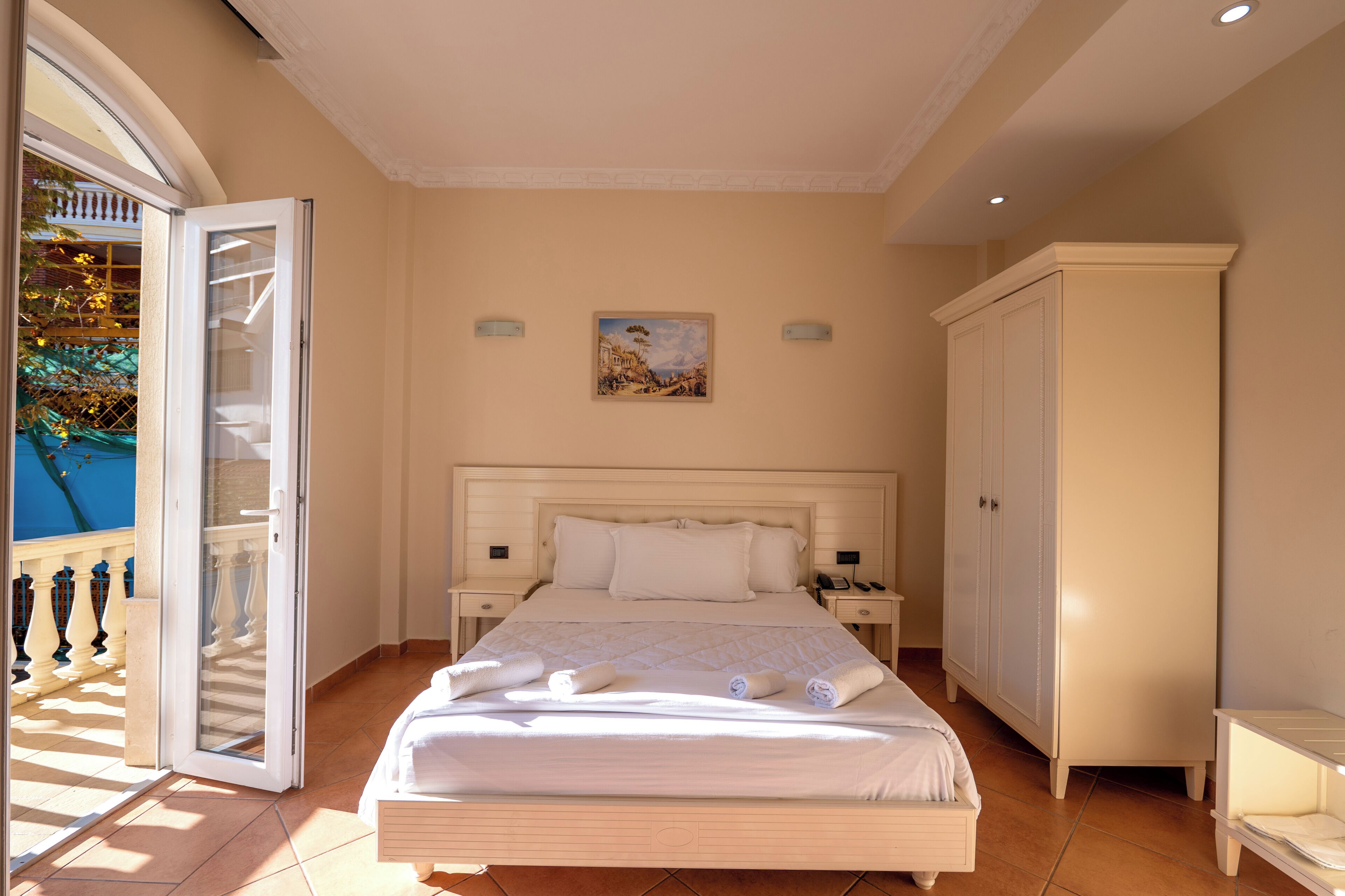 Un dormitorio con cama, mesitas de noche, un armario y un cuadro en la pared.