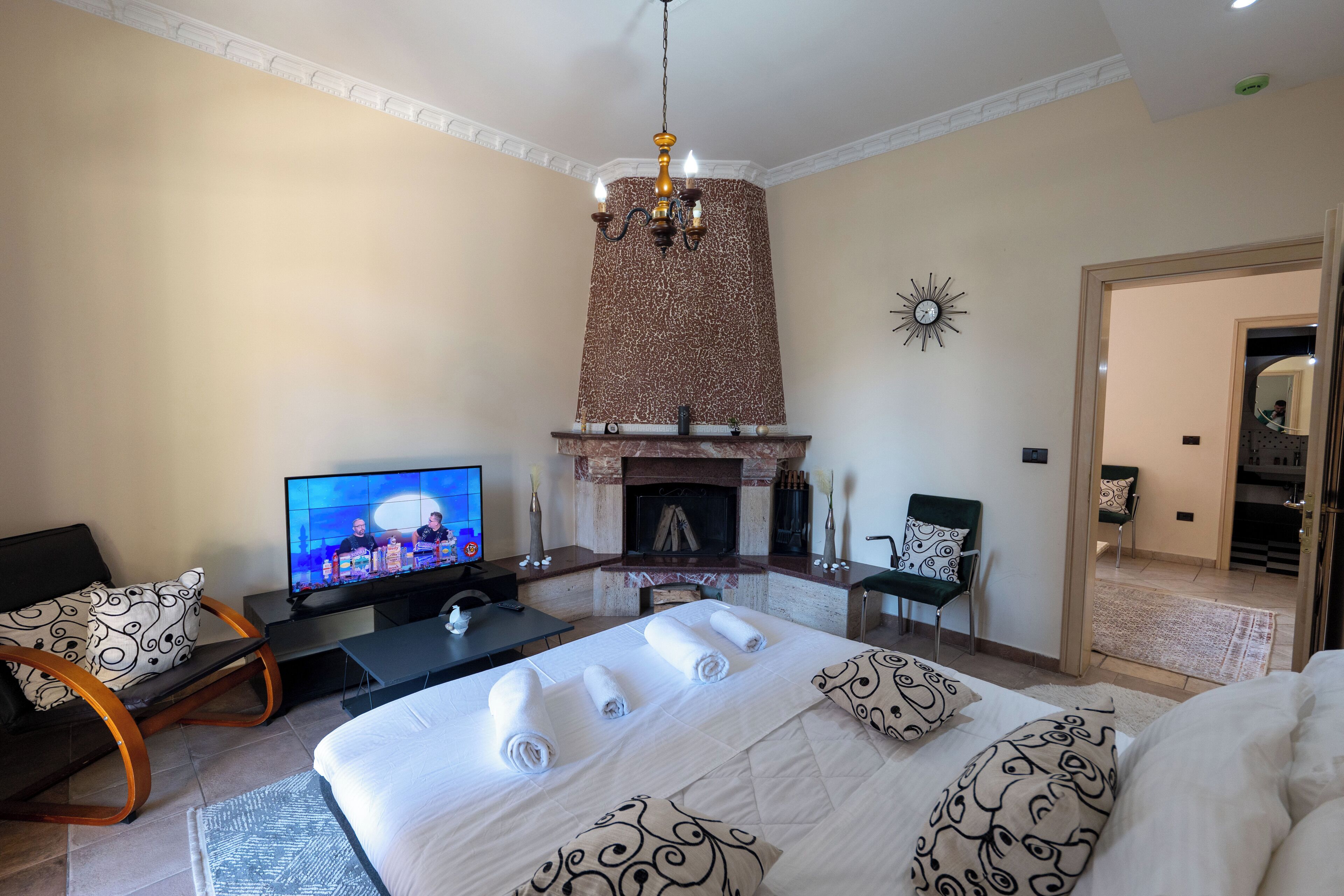 Quarto de hotel com uma cama grande, televisão, lareira e área de jantar.