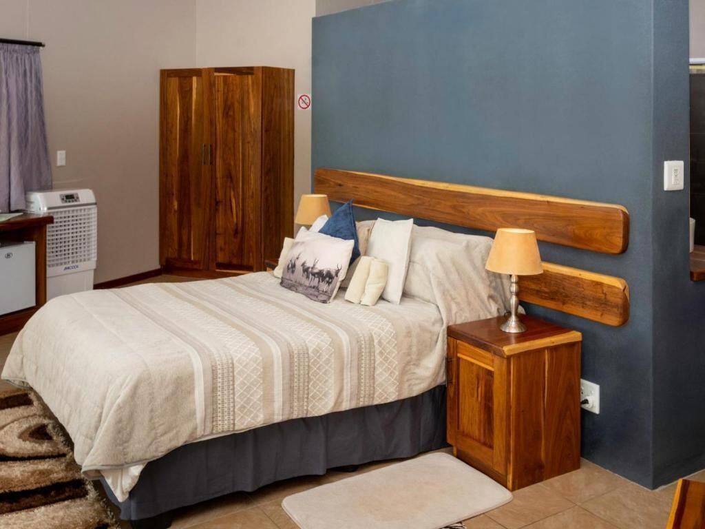 Une chambre à coucher avec un lit, une tête de lit en bois, des tables de chevet et un tapis.