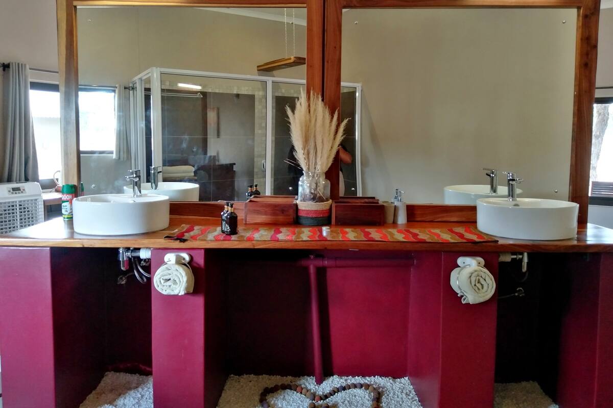 Een badkamer met twee wastafels, een grote spiegel en een handdoekrek.