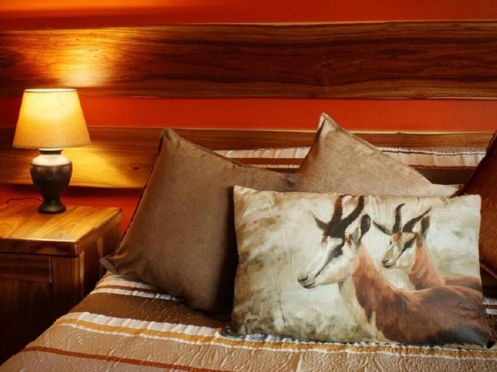 A bed with striped bedding, two pillows, and a nightstand with a lamp.