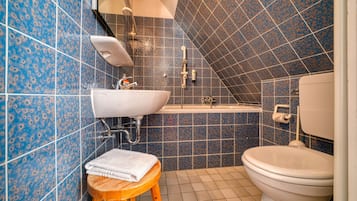Ein Badezimmer mit Waschbecken, Toilette und einem hölzernen Hocker.