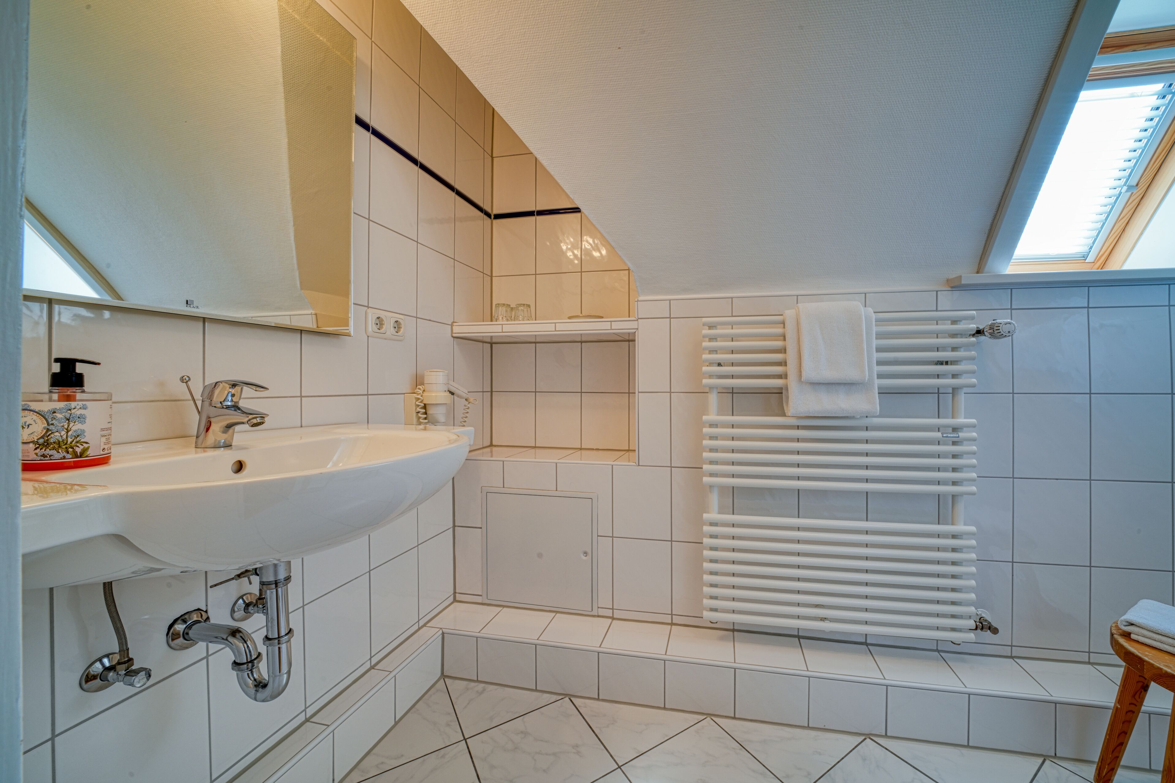 Een moderne badkamer met een groot wastafel, een spiegel, een handdoekhouder en een dakraam.